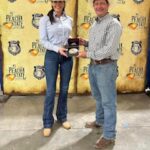 Two people in cowboy hats holding an award.