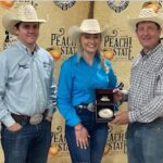 Three people in cowboy hats, woman holding award.