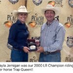 Woman and man in cowboy hats, holding a trophy.