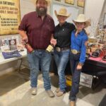 Three people wearing cowboy hats and holding bottles.