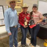 Three people smiling at a rodeo event.